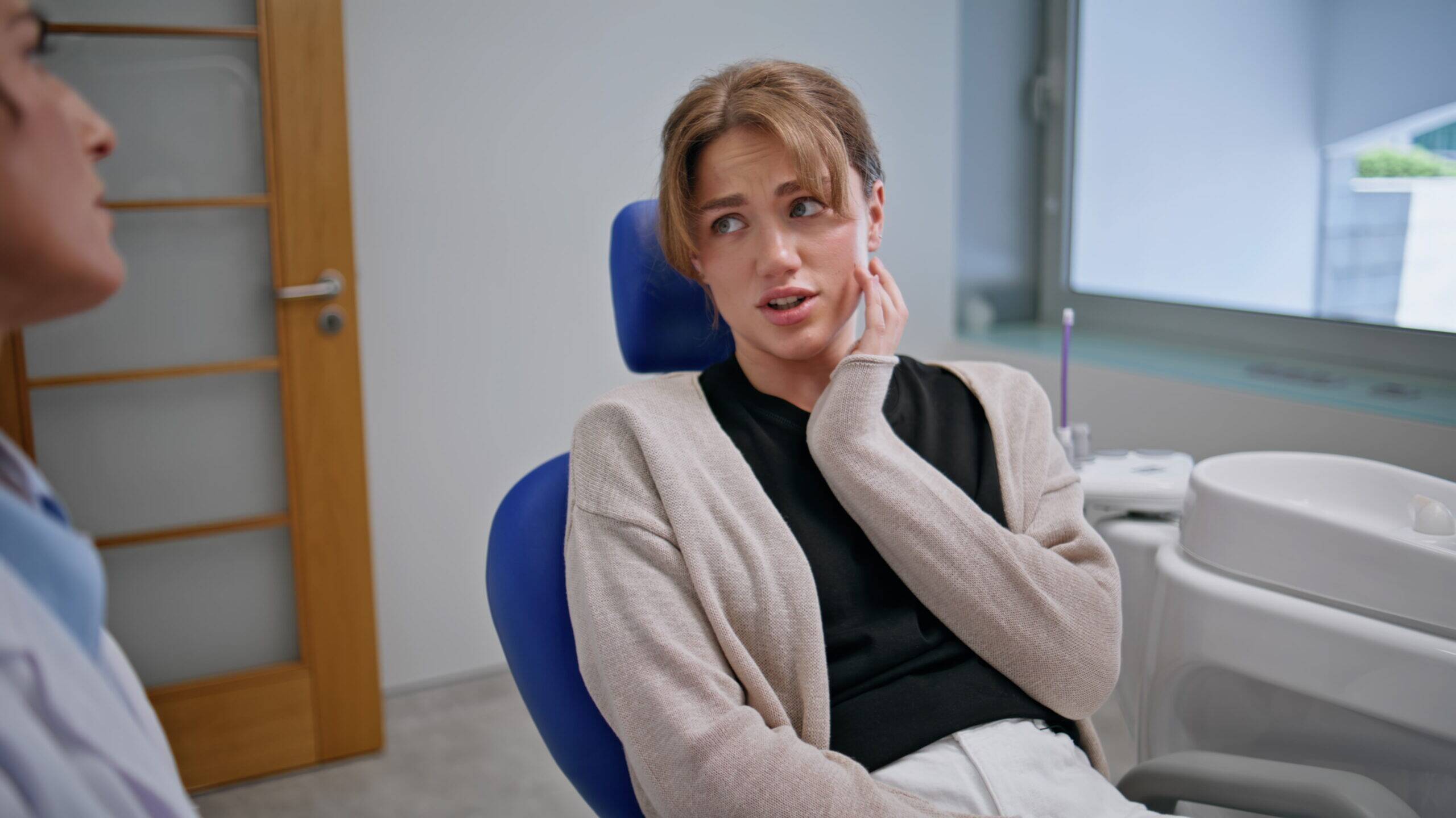 Patient complaining at dental pain in stomatology appointment closeup. Attentive woman dentist listening clinic visitor in chair. Young lady feeling toothache talking with professional stomatologist.