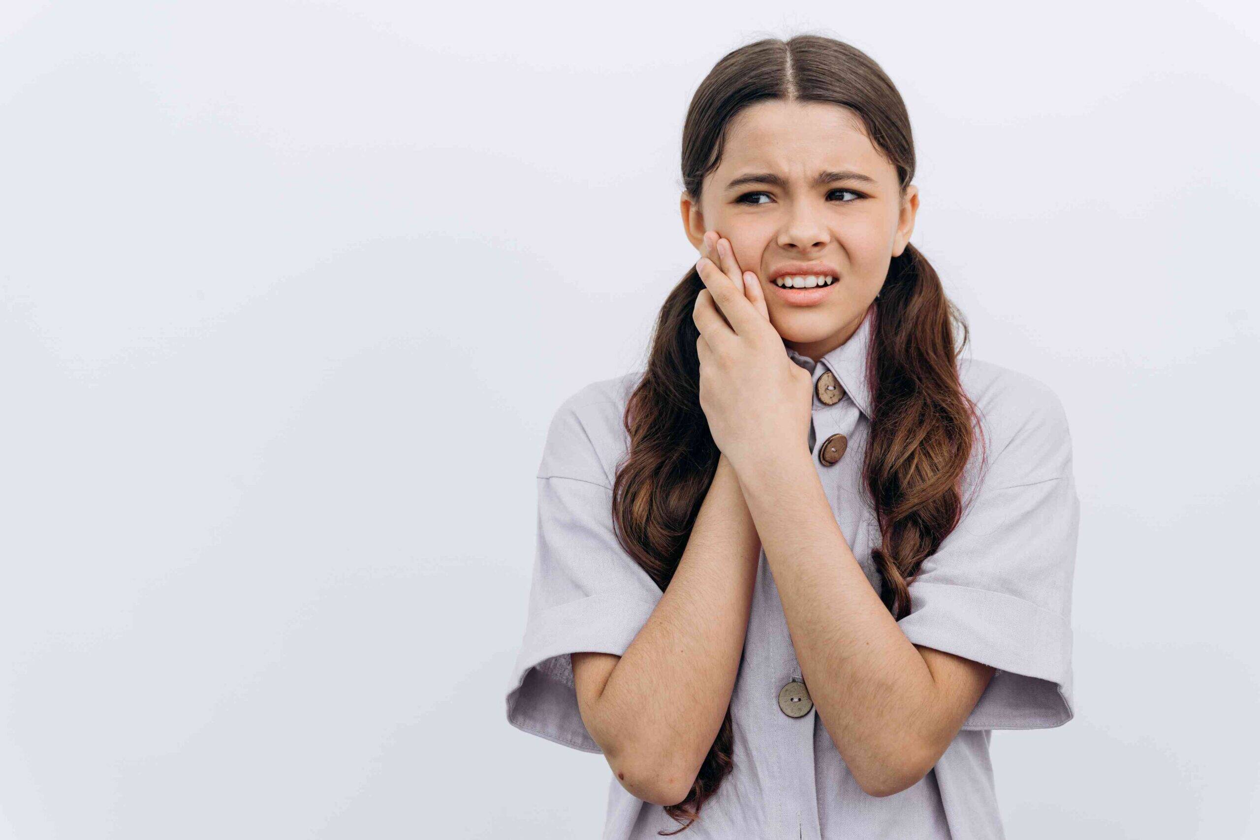 Young girl holding her cheek with a toothache.